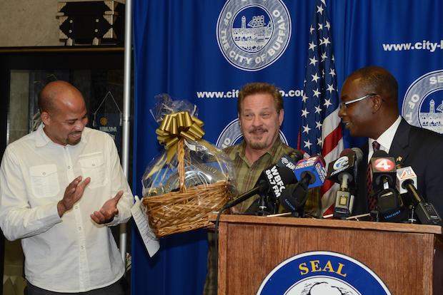 At the podium during the 7/16 press conference welcoming film director Fred Olen Ray back to Buffalo are: (l. to r.) line producer Gerald Webb, Olen Ray (holding a City of Buffalo gift basket presented by Mayor Brown, and Mayor Byron Brown. Not pictured: Tim Clark, Buffalo Niagara Film Commissioner. Photo: Nancy J. Parisi

