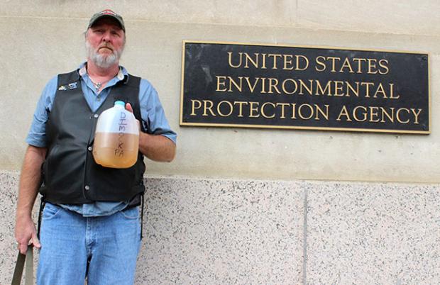 Dimock, Pennsylvania resident Ray Kemble&nbsp;holds a jug of discolored water from his well, contaminated by nearby fracking operations while standing outside of the U.S. EPA building in Washington, DC. Photo credit: Food &amp; Water Watch
