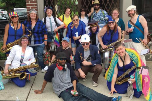 Brass Pro &amp; the Waterfront Revivalists, led by baritone saxophonist Kim Saben (front row, left) is a 10-15-member “party band with a marching problem.”
